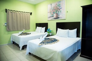 Une chambre d’hôtel avec deux lits, un tableau représentant des fleurs, un rideau et un meuble noir.