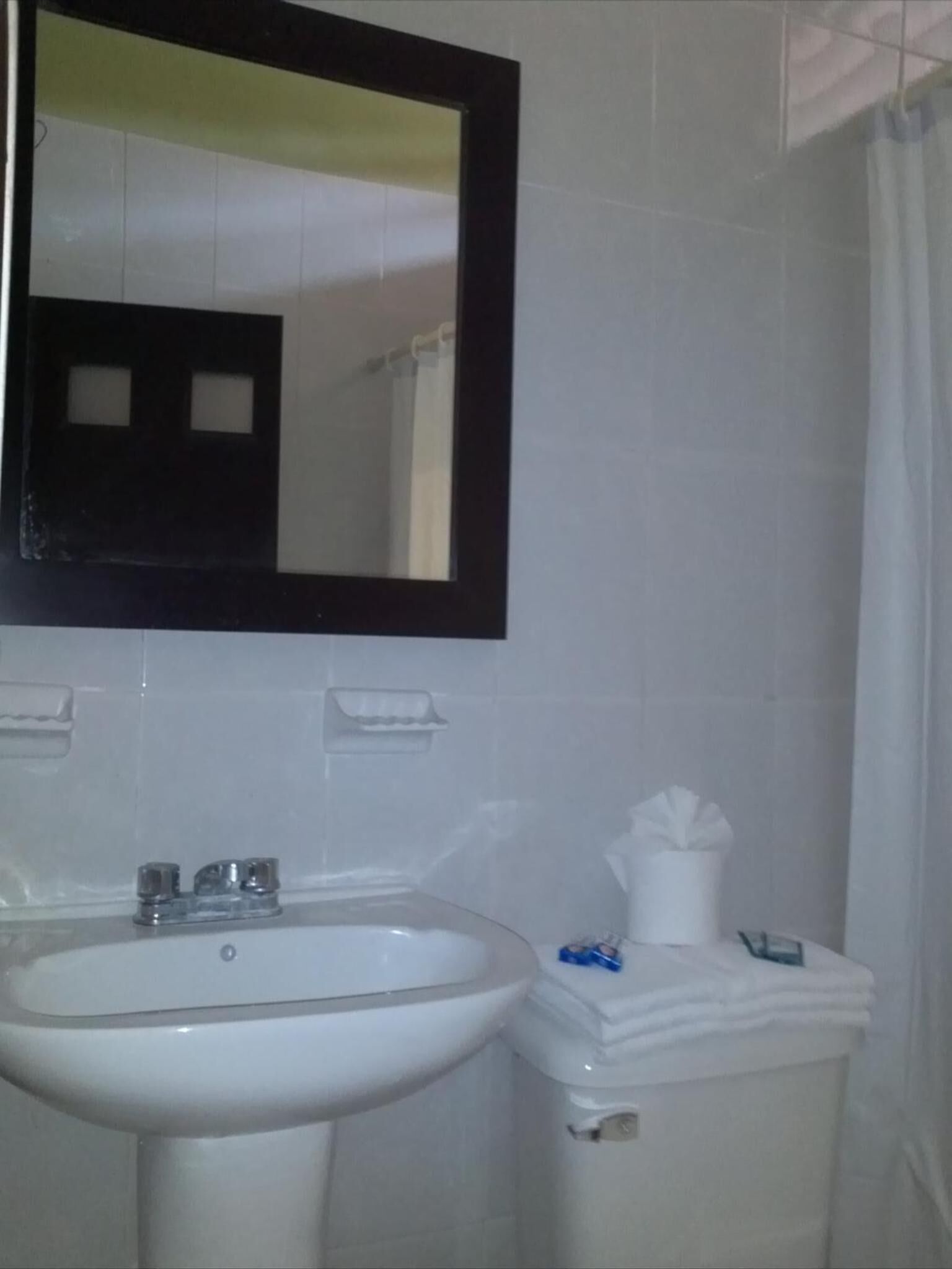 Un baño con un lavabo blanco, un espejo y un inodoro.