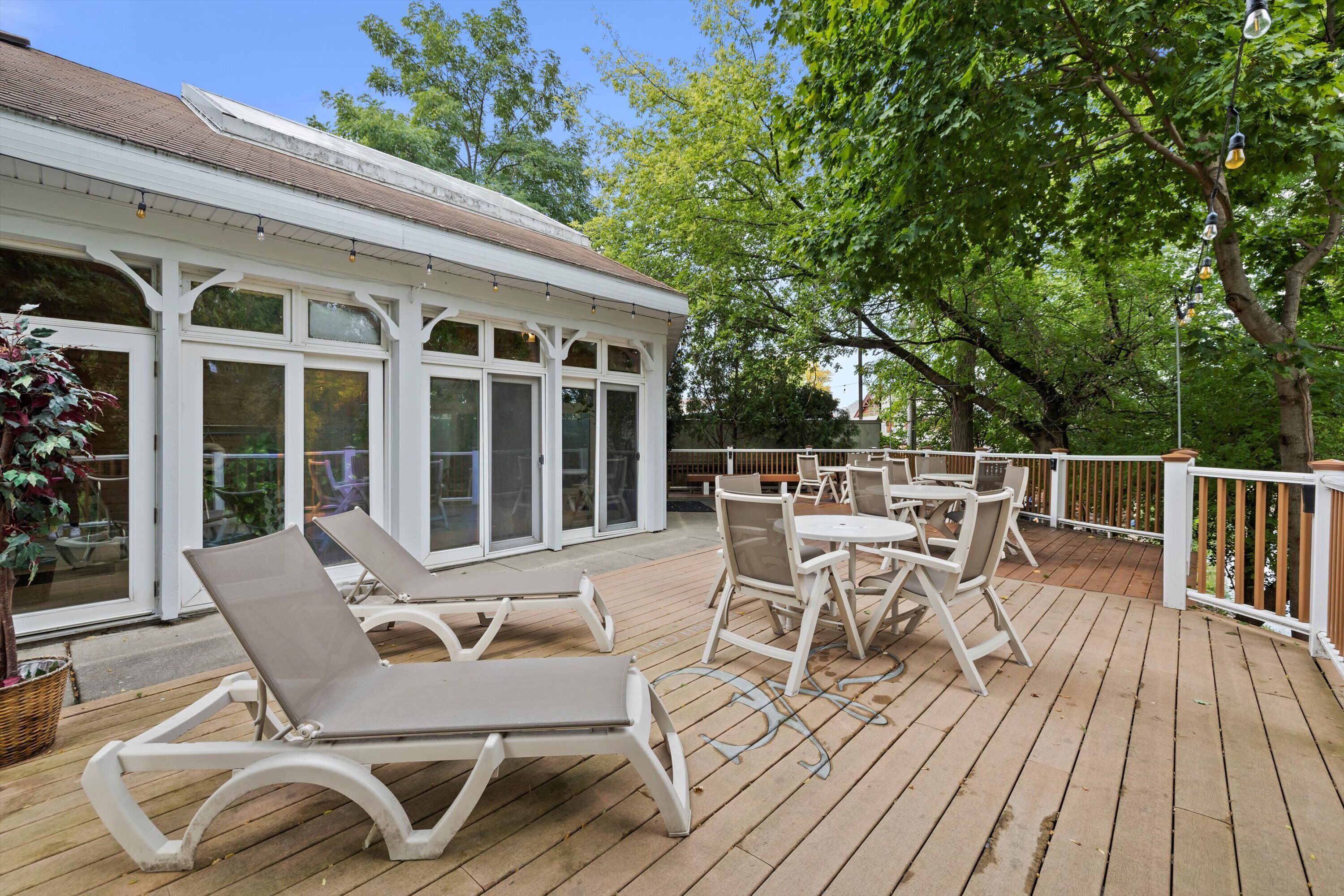 Une terrasse extérieure couverte, dotée de chaises longues et de tables, et entour ée d’arbres.
