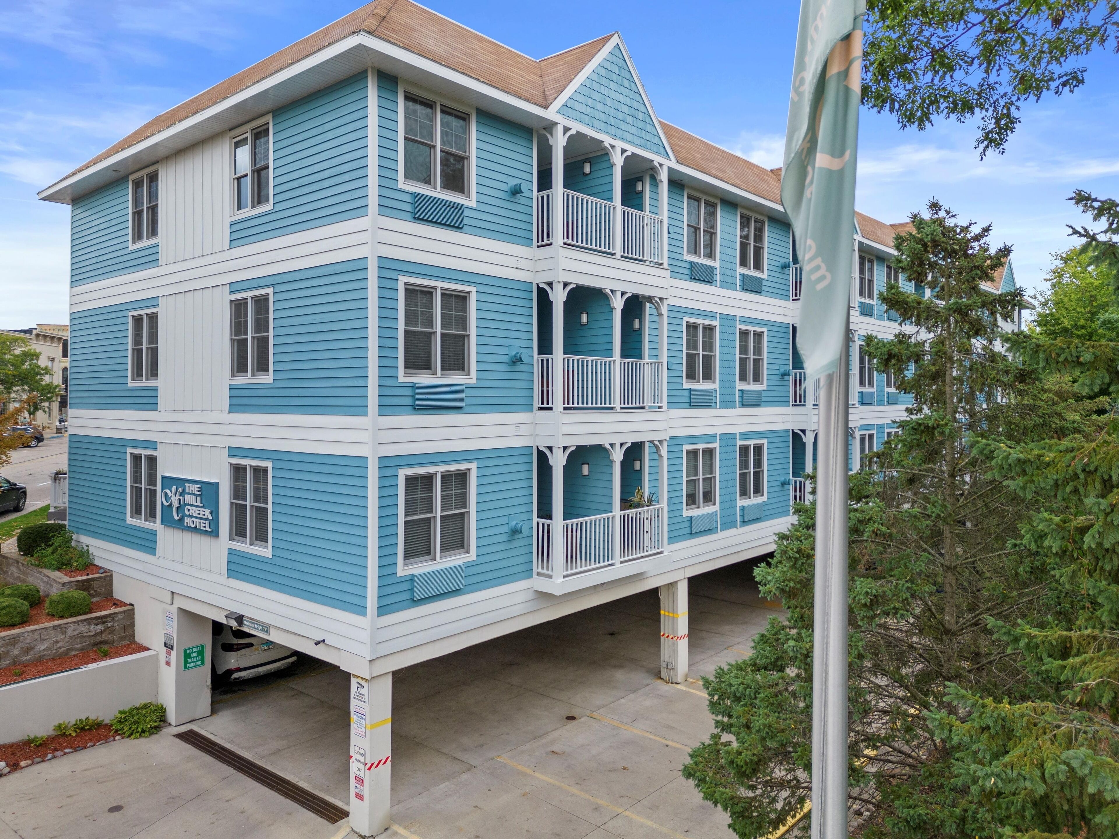 A multi-story hotel with a blue and white exterior, balconies, and a sign indicating it is The Mill Creek Hotel.