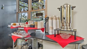 A coffee bar with a stainless steel espresso machine, cups, and a sign that reads "Coffee Bar".