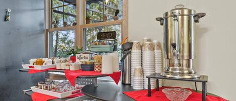Una cafetería con una máquina de espresso de acero inoxidable, tazas y un cartel que dice 'Coffee Bar'.