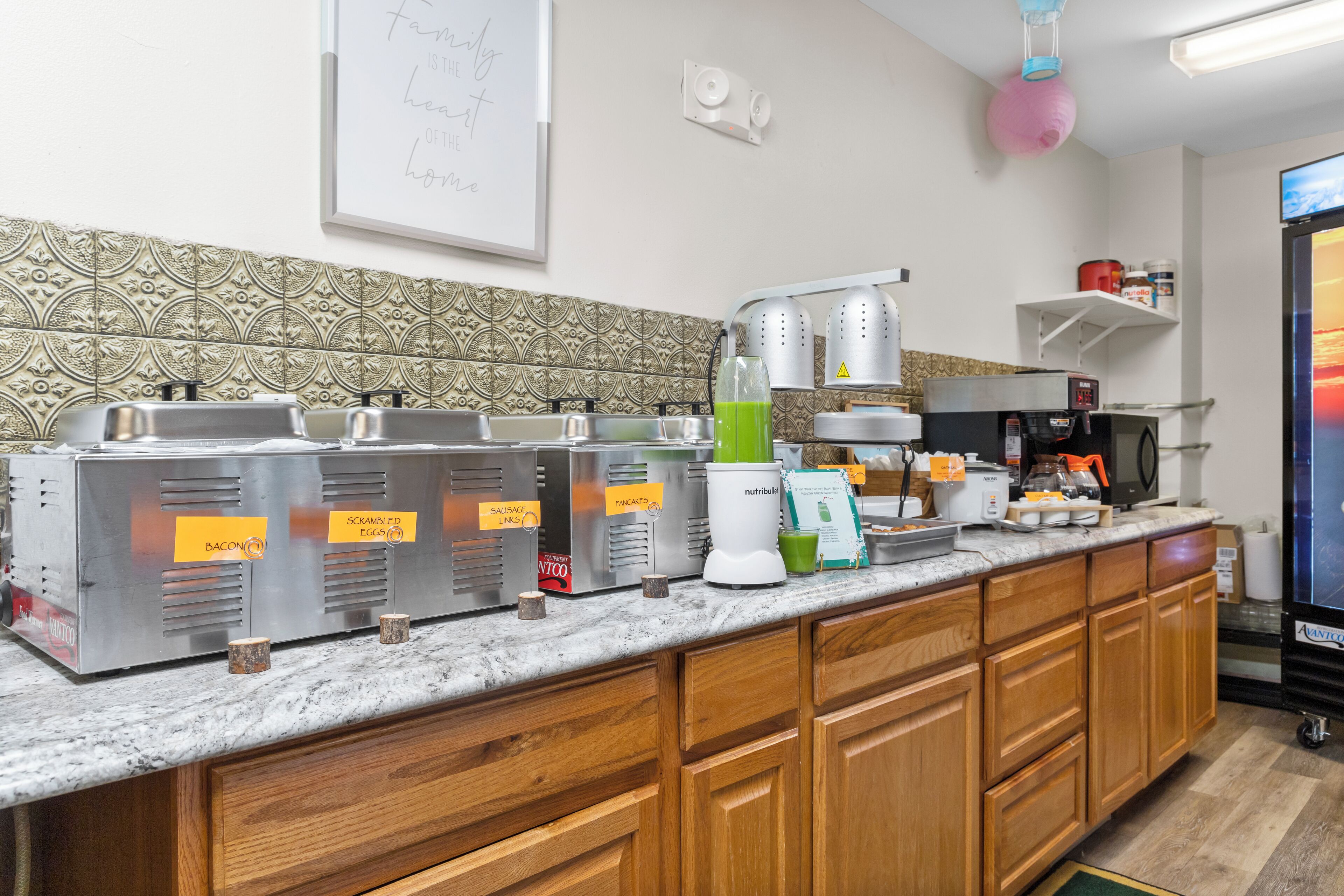 A breakfast bar with various food stations, including bacon, scrambled eggs, and sausage links.