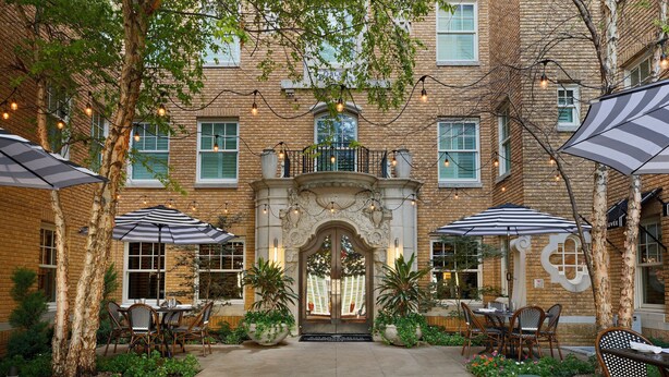 A courtyard with outdoor seating, a brick building, and string lights. - Ambassador Hotel Oklahoma City, Autograph Collection (Oklahoma City)
