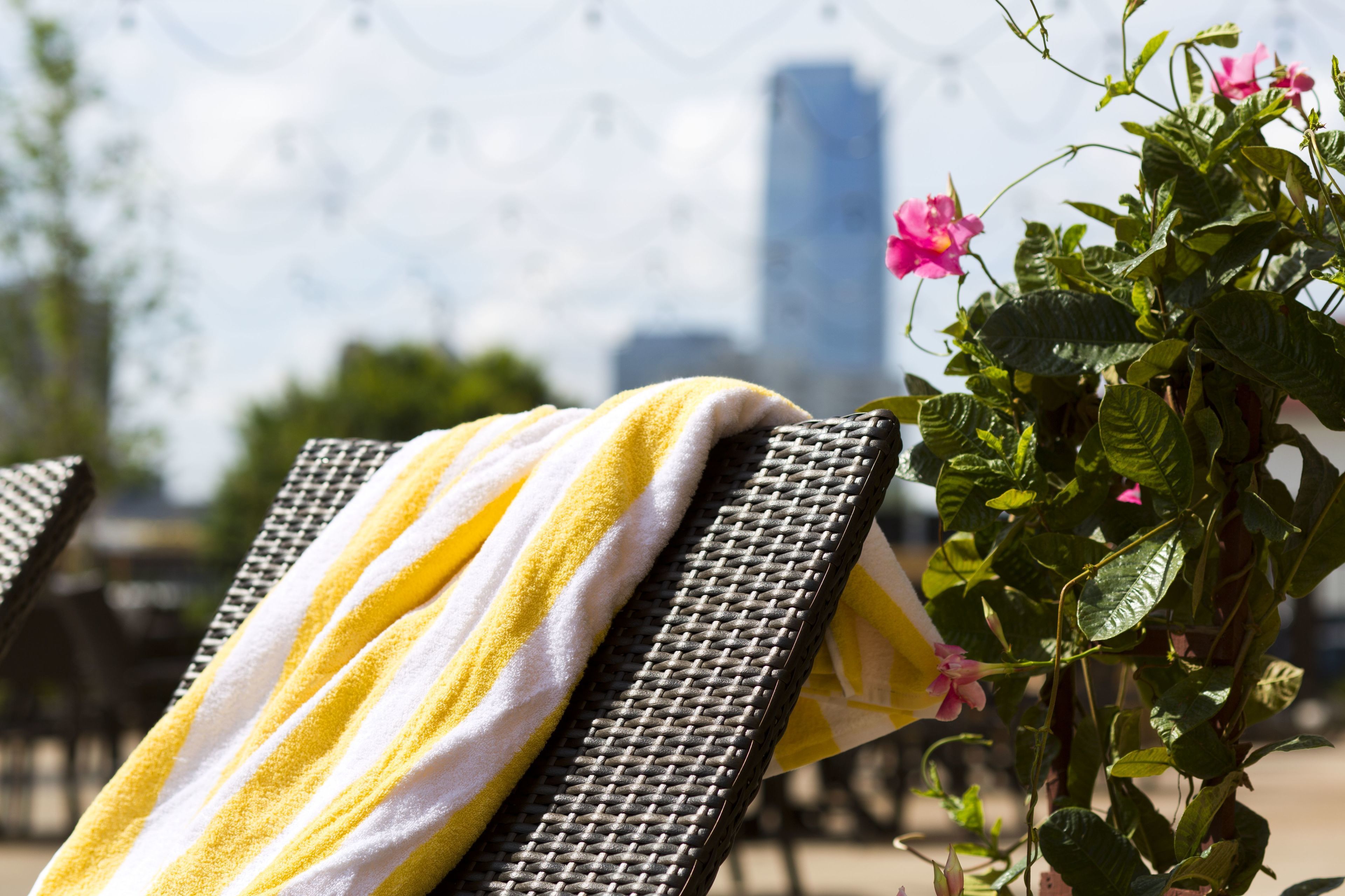 A wicker lounge chair with a yellow and white striped towel.