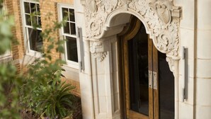 A building entrance with ornate stonework, a wooden door, and potted plants. - Ambassador Hotel Oklahoma City, Autograph Collection (Oklahoma City)