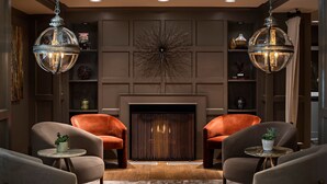 A modern living room with two leather armchairs, a small round table, and a fireplace.