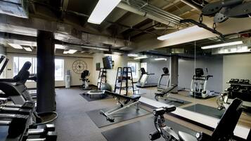 Une salle de sport équipée de divers appareils d’exercice, notamment des tapis de course, des appareils de musculation et des poids libres.