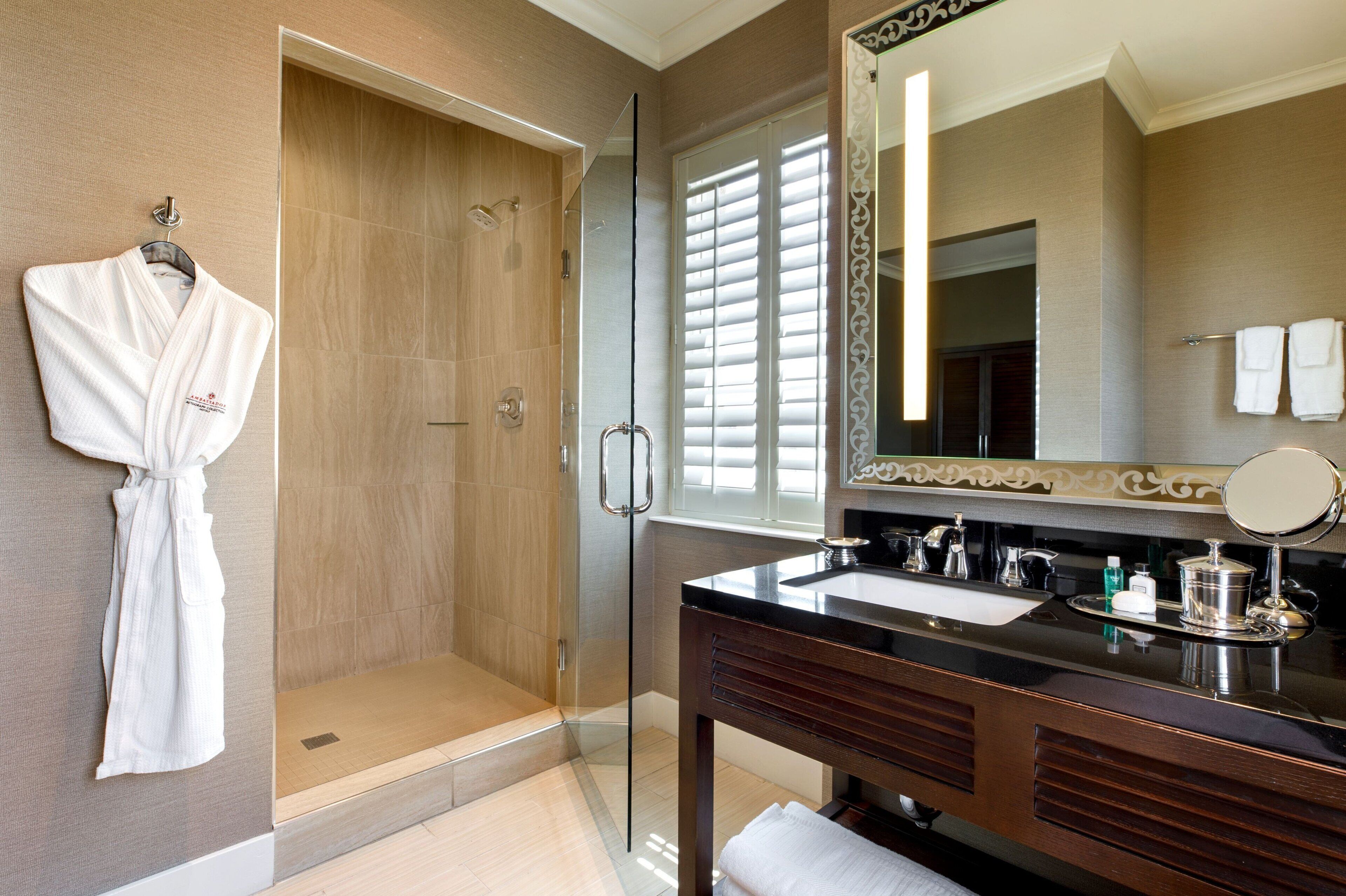 A modern bathroom with a glass-enclosed shower, a large mirror, and a dark wooden vanity.