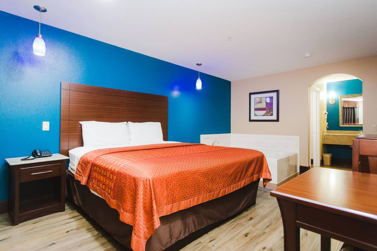 A hotel room with a bed, bedside table, and a desk.