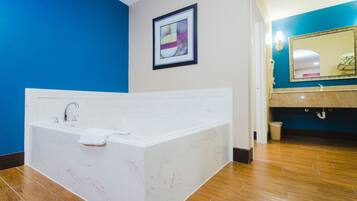 A modern bathroom with a large bathtub, a sink, and a mirror.