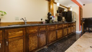 A kitchen with wooden cabinets, a granite countertop, and a stainless steel refrigerator. - Home Place Inn (Houston)