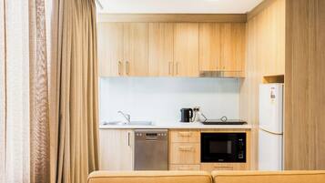 A compact kitchen with wooden cabinets, a dishwasher, a microwave, and a refrigerator.