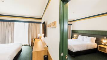A hotel room with two beds, a desk, and a mirror.