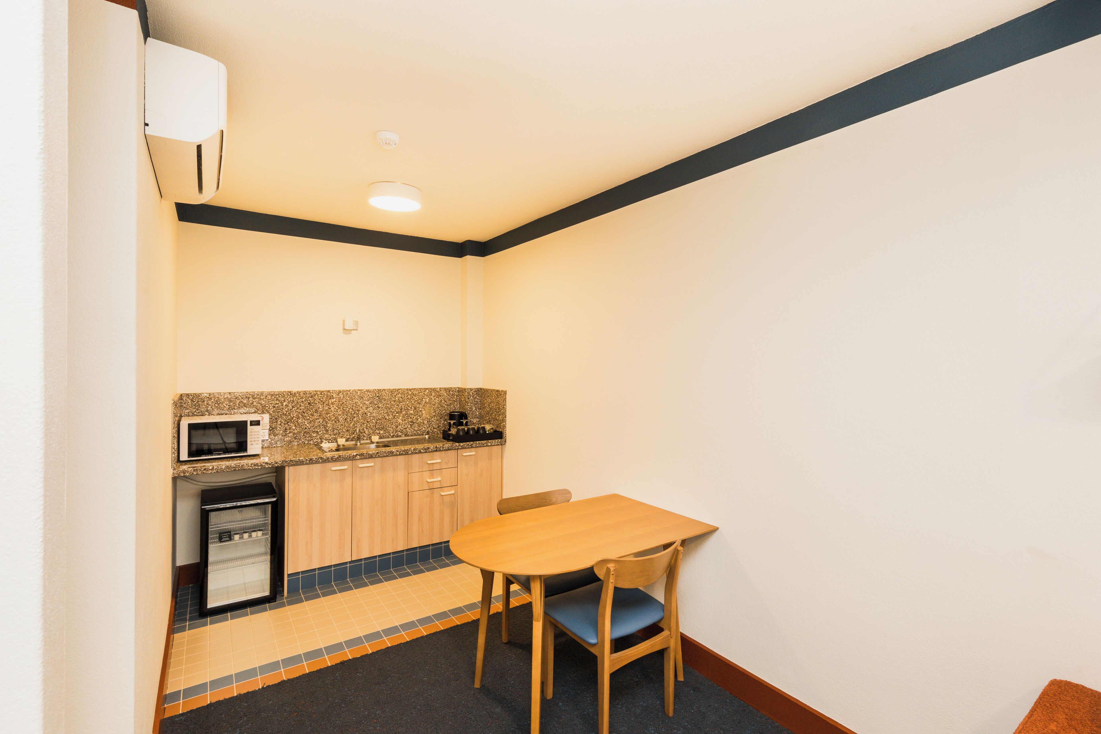 A compact kitchen with a microwave, refrigerator, and a small coffee maker.