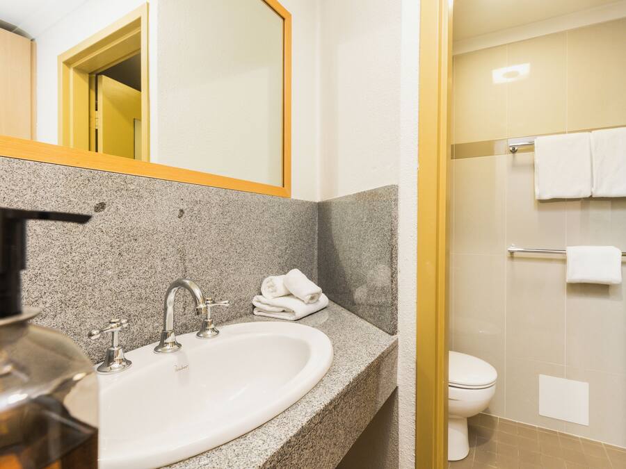 A bathroom with a granite countertop sink, a mirror, and a shower area with a glass door.
