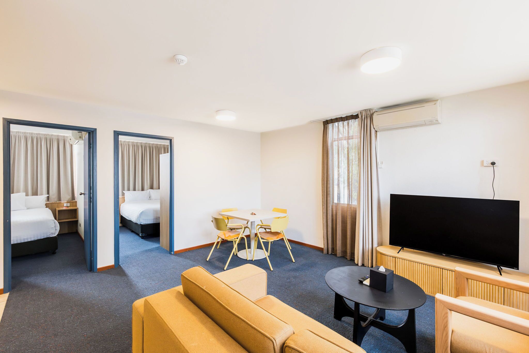 Une chambre d’hôtel avec deux lits, un coin repas, une télévision et un canapé.