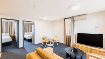 Une chambre d’hôtel avec deux lits, un coin repas, une télévision et un canapé.