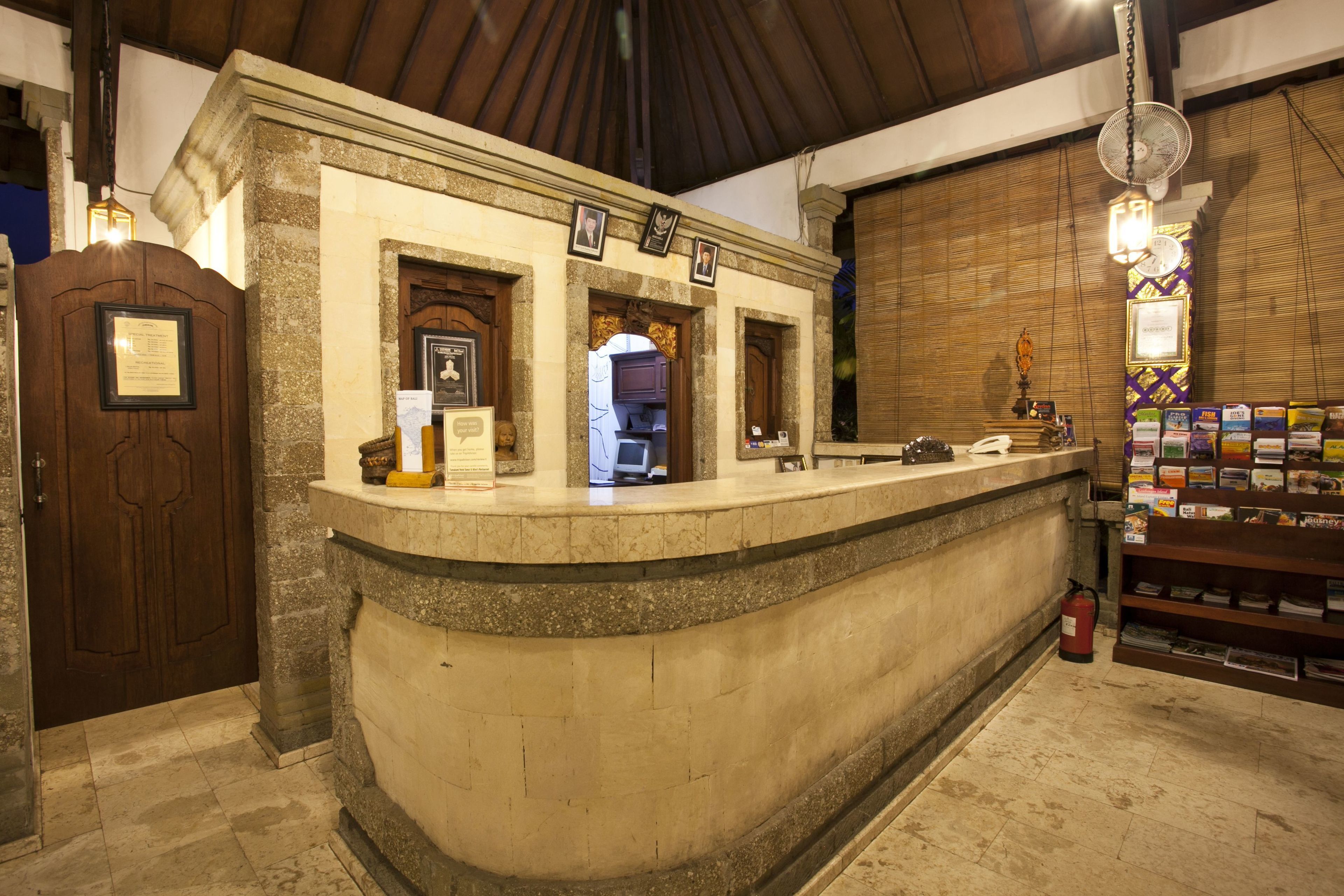 A reception area with a stone counter, framed pictures, a fire extinguisher, and a shelf with magazines.