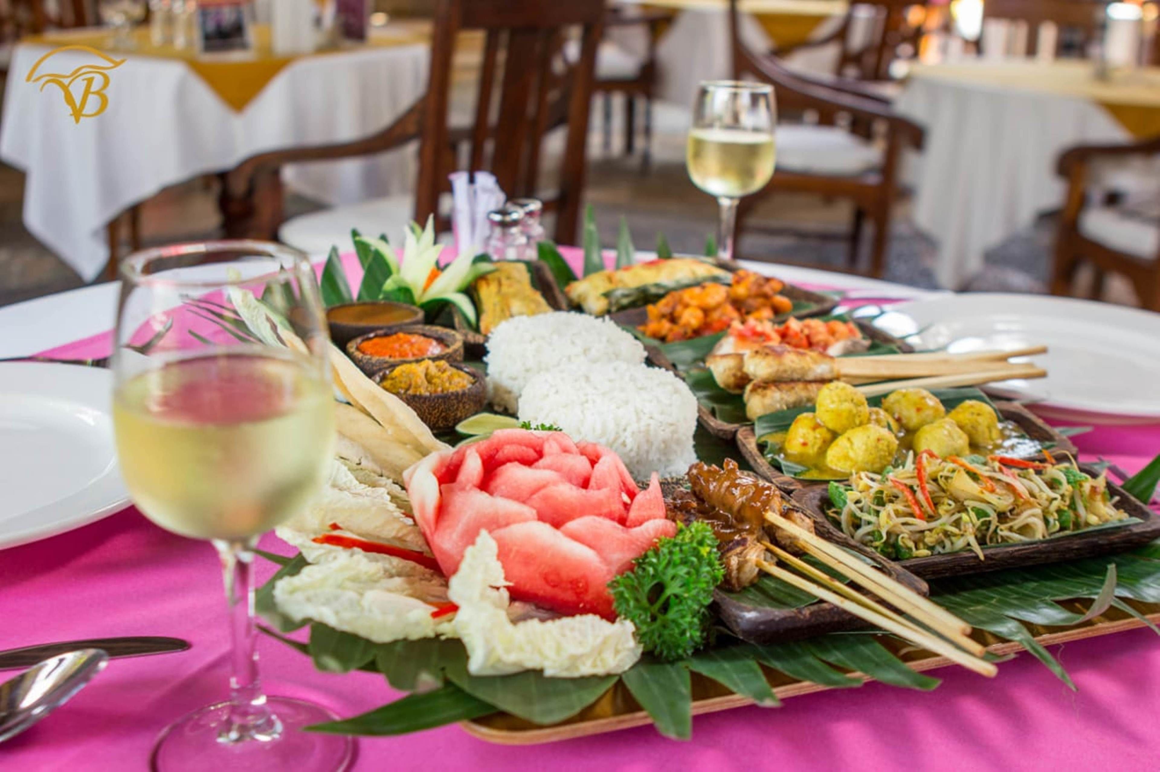 A table set with a variety of dishes, including rice, vegetables, and meat, along with a glass of white wine.