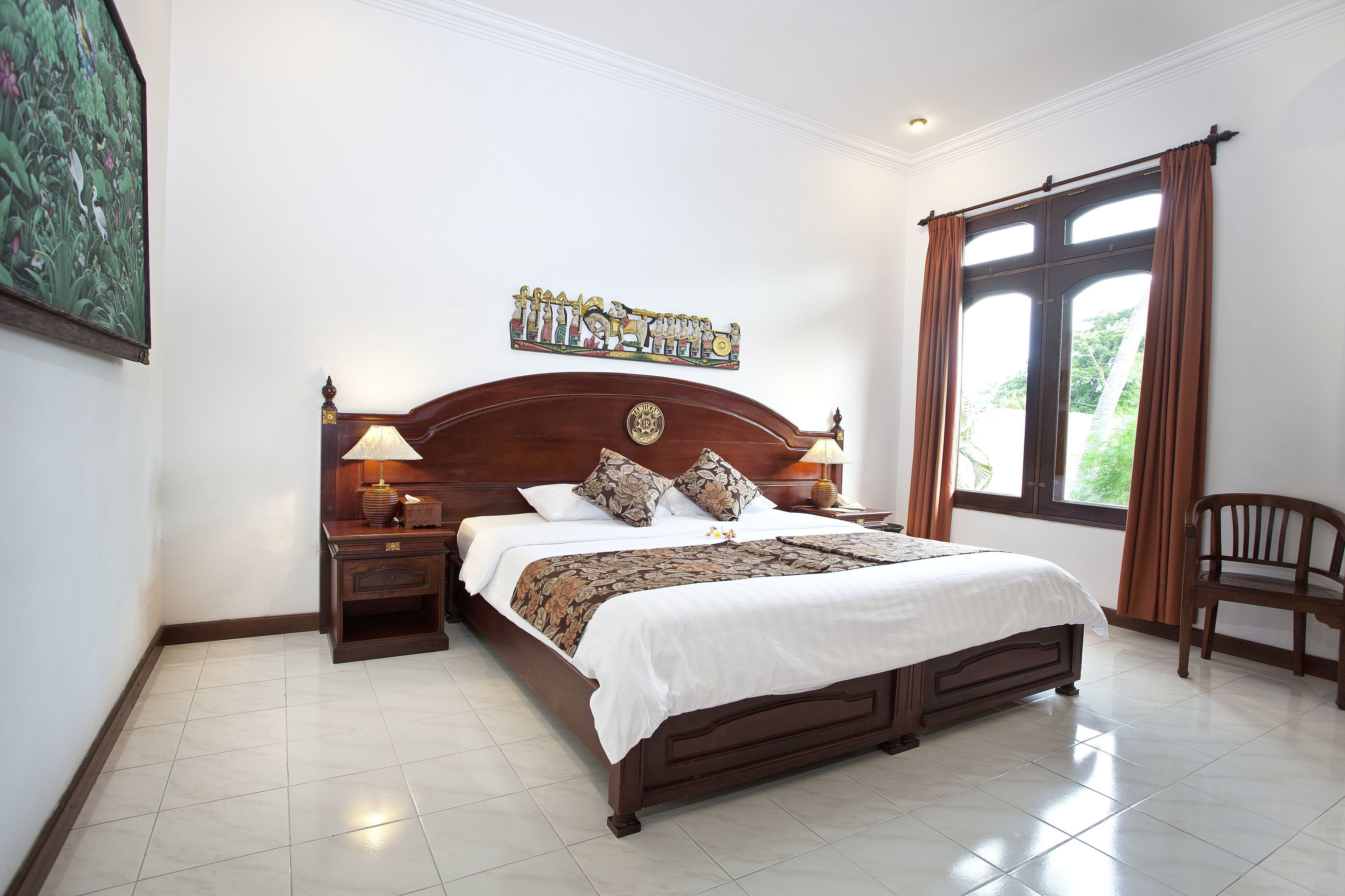 A neatly made bed with a wooden headboard, two bedside tables with lamps, a decorative wall piece, and a window with curtains.