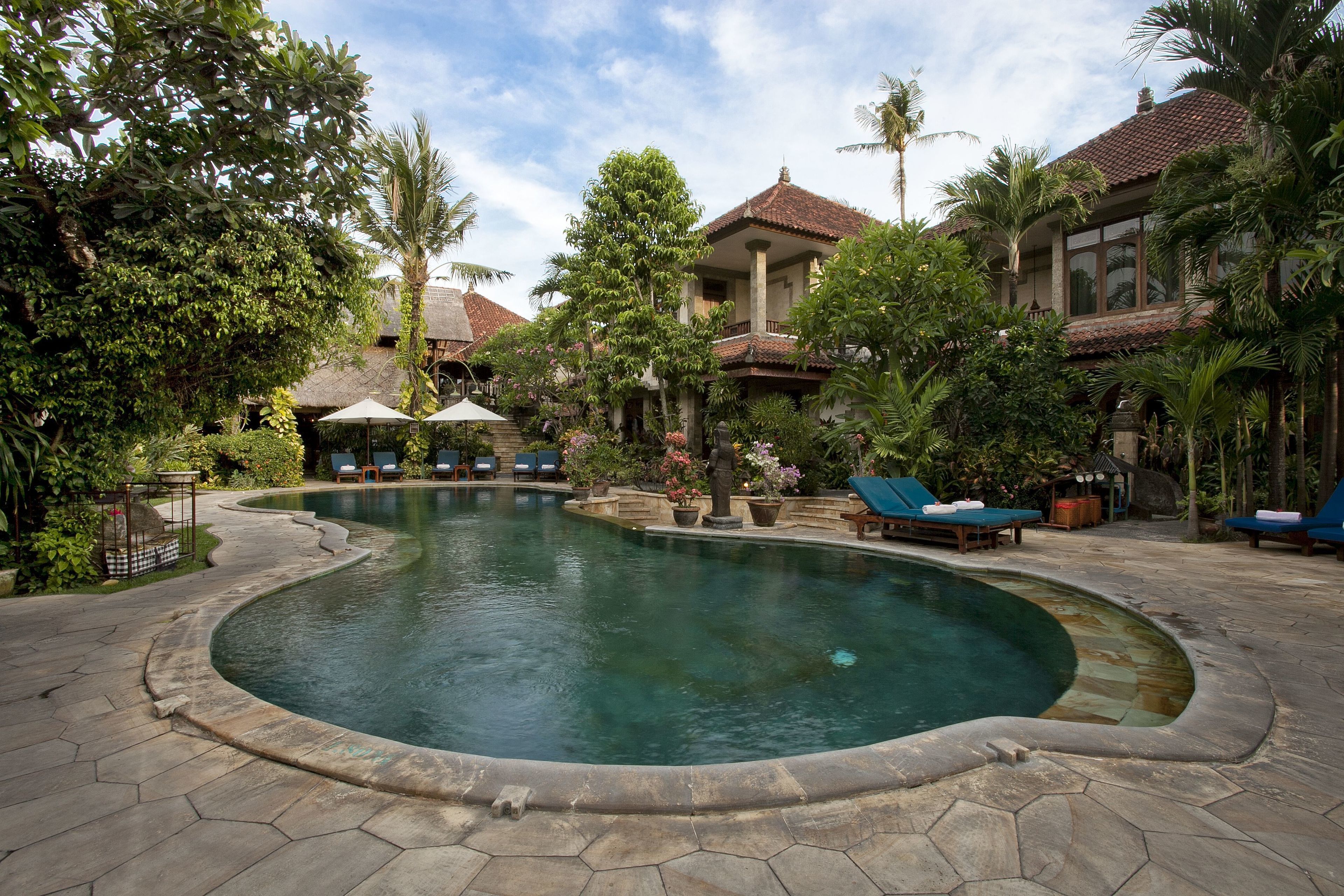 A swimming pool with lounge chairs and a tropical garden.