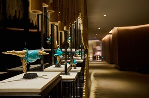 A corridor with a series of tables displaying sculptures. - The Mulian Hotel Guangzhou Zhujiang New Town (Guangzhou)