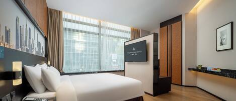 Habitación de hotel moderna con una cama grande, un televisor de pantalla plana, un escritorio con teléfono y vistas a la ciudad.