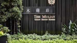 Un letrero del Hotel Mulian Urban Resort, con fachada negra vertical y un emblema decorativo.