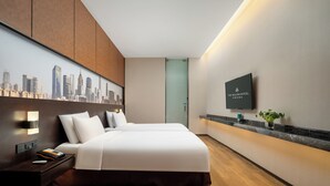 Una habitación de hotel moderna con una cama grande, un mural de paisaje urbano, un televisor de pantalla plana y una mesita de noche de madera.