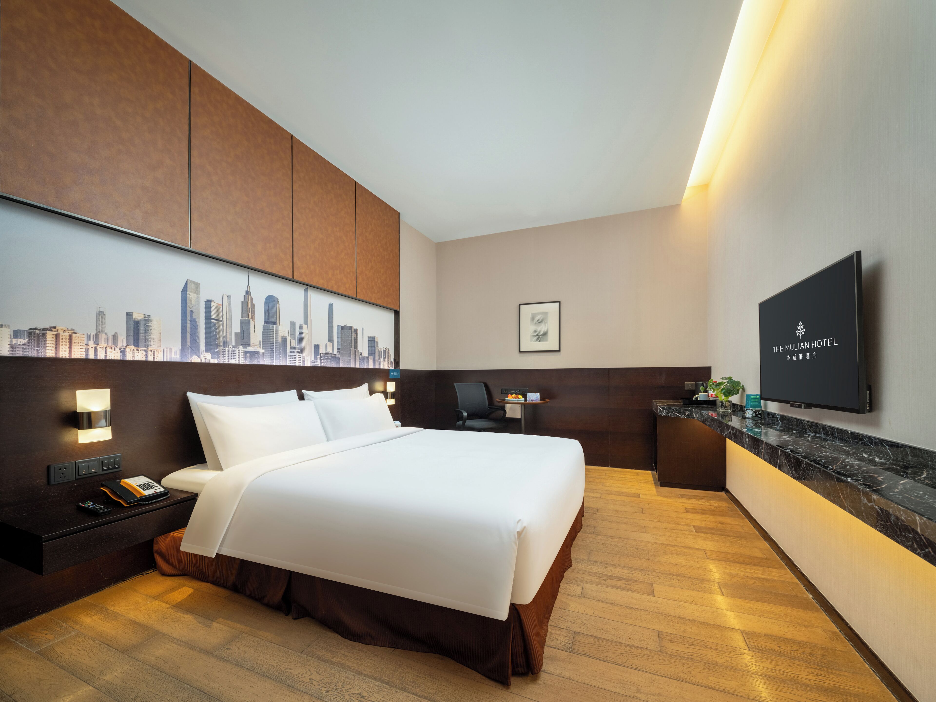 Habitación de hotel con cama, escritorio, televisor de pantalla plana y vista panorámica de la ciudad.