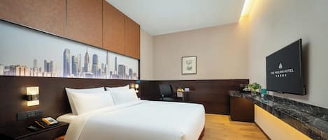 Habitación de hotel con cama, escritorio, televisor de pantalla plana y vista panorámica de la ciudad.