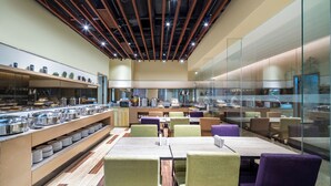 Un restaurante moderno con una barra larga, varias zonas de estar y una pared divisoria de vidrio.