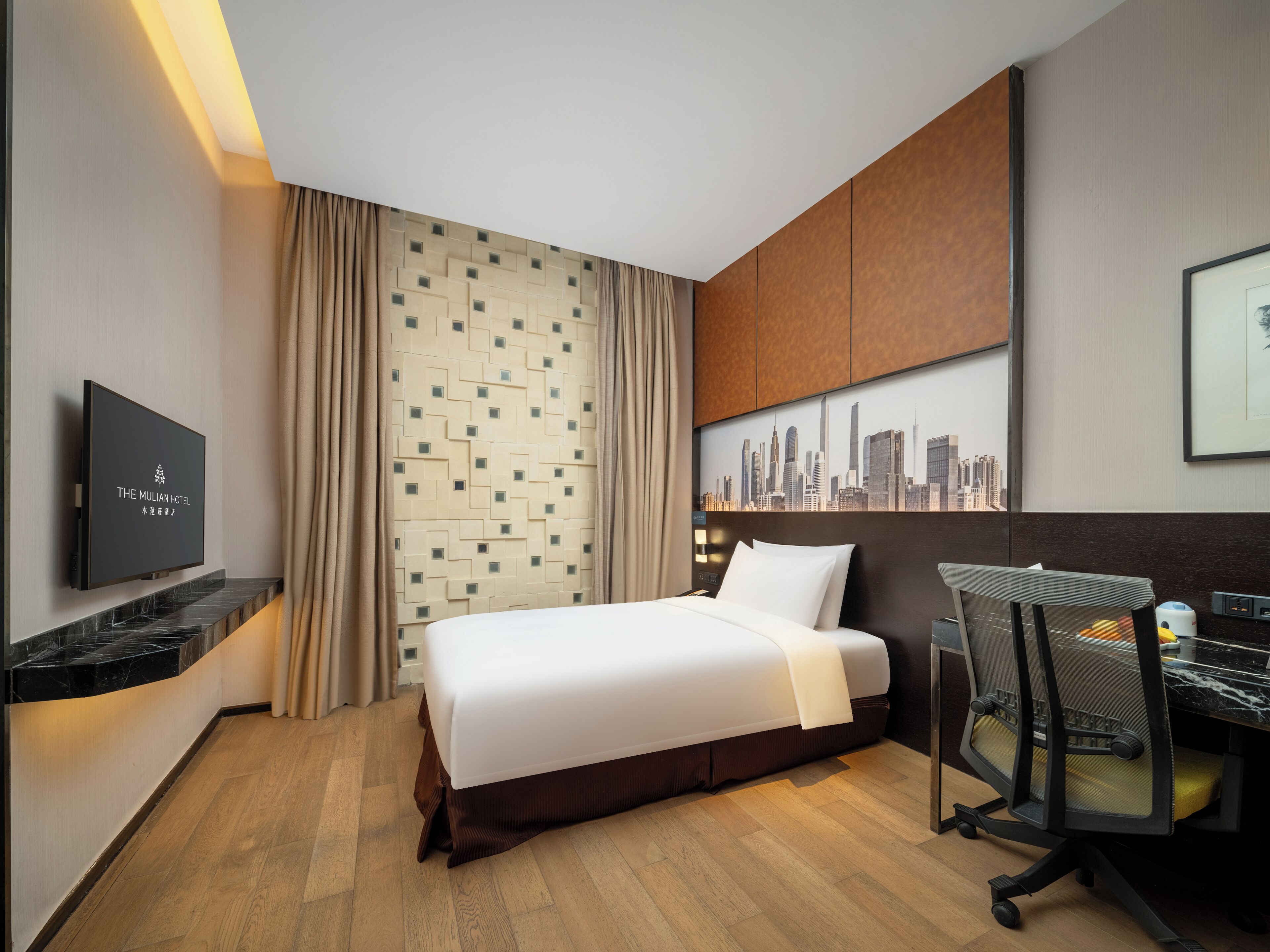 Une chambre d’hôtel avec un lit, un bureau, une chaise, une télévision et une vue sur la ville.