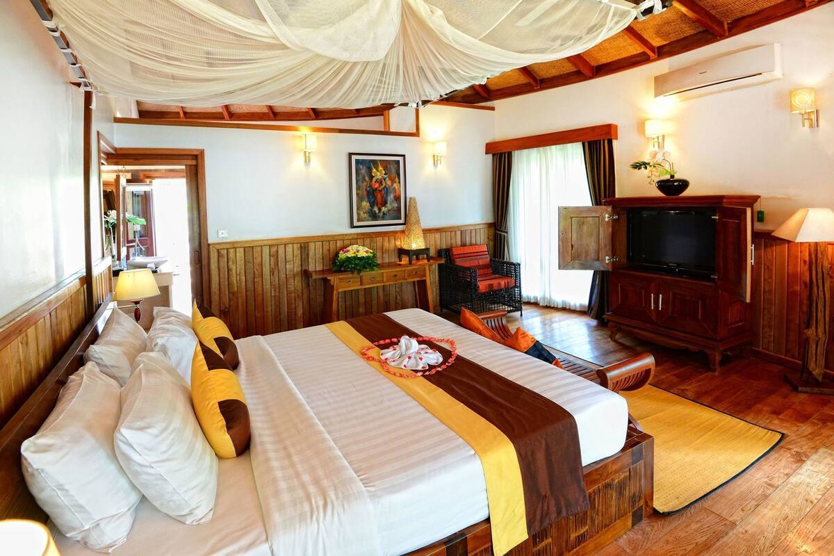 A hotel room with a bed, a television, a wooden cabinet, a desk, and a chair.