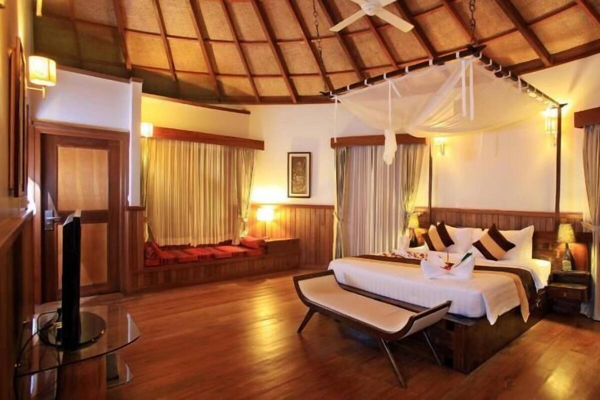 A spacious room with a large bed, a sitting area, and a ceiling fan.