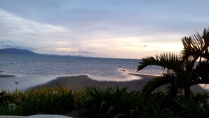 A beach view with a wooden deck, a woven basket, and tropical plants. - Nataya Roundhouse Coral Bay Resort and Spa (Kampot)