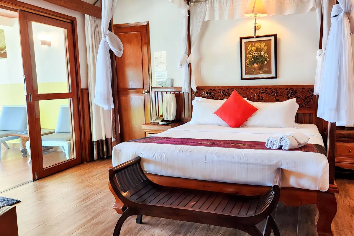 A hotel room with a bed, a bench, a desk, and a chair.