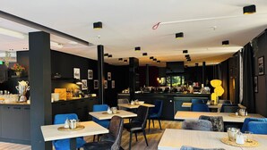 A modern restaurant interior with dark walls, blue seating, and a bar area with various items displayed. - DORMERO Schwäbisch Hall (Schwäbisch Hall)