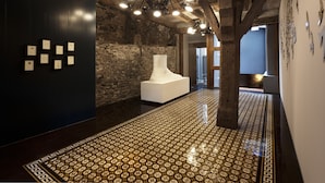 A hallway with a patterned floor, a white sculptural piece, and framed certificates on the wall. - DORMERO Schwäbisch Hall (Schwäbisch Hall)