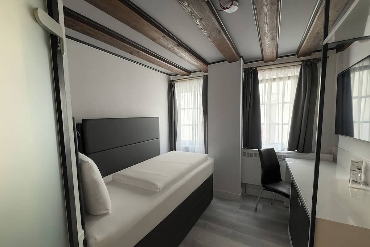 Een moderne hotelkamer met een bed, een bureau en een stoel.