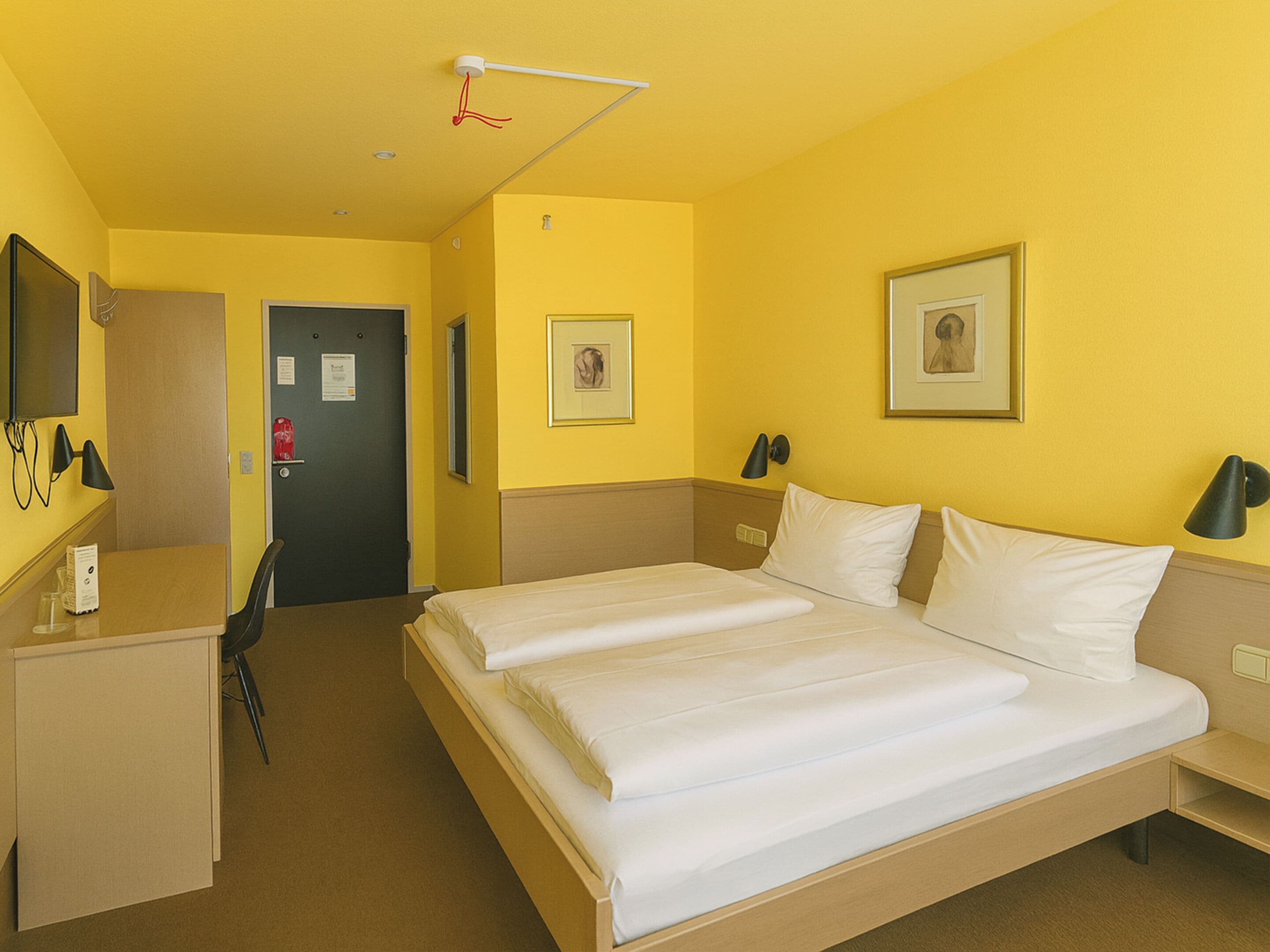 Une chambre d’hôtel avec un grand lit, un bureau, une chaise et une porte.
