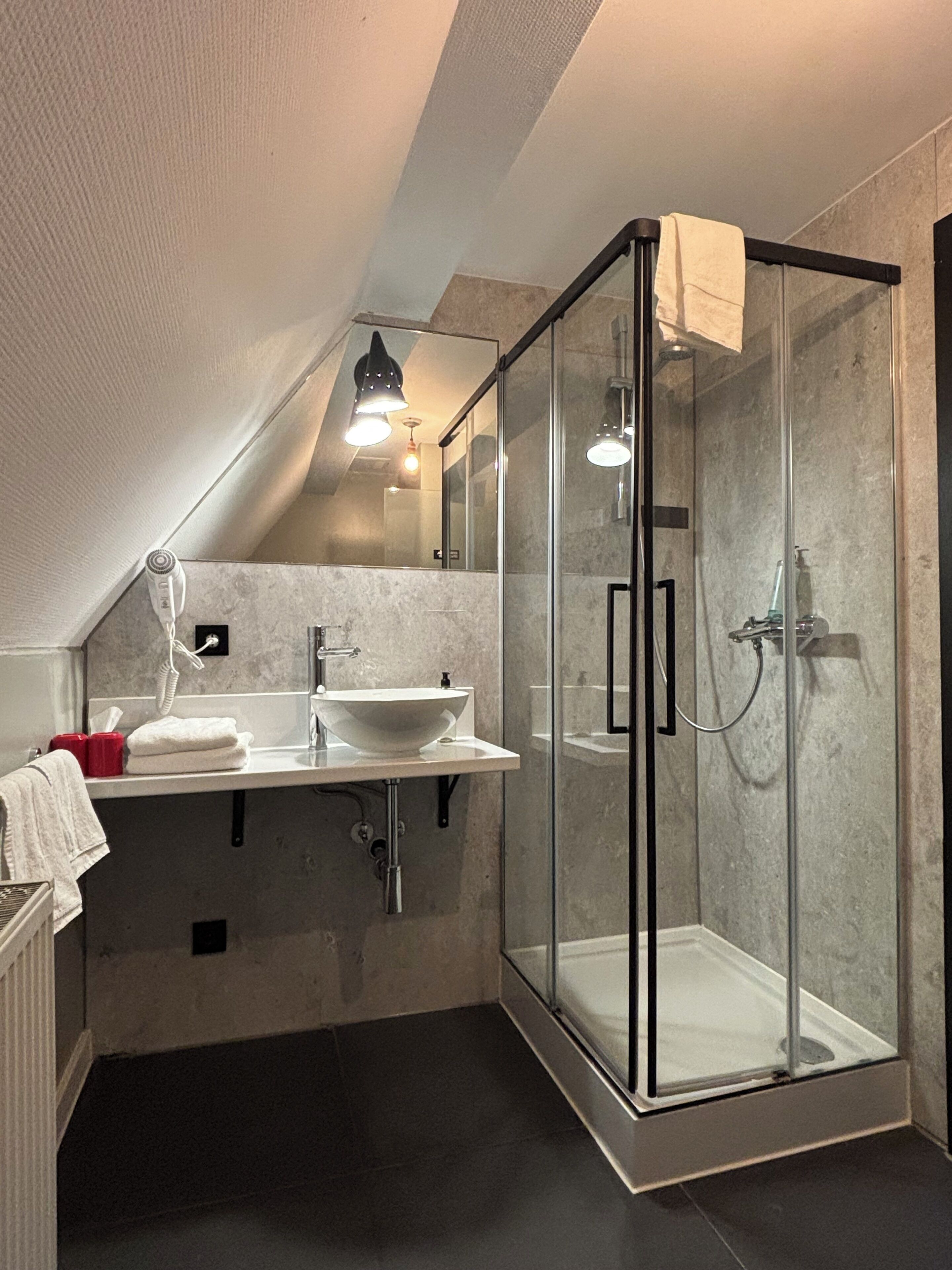 Een moderne badkamer met een glazen douchecabine, een wit wastafelmeubel en een handdoekrek.