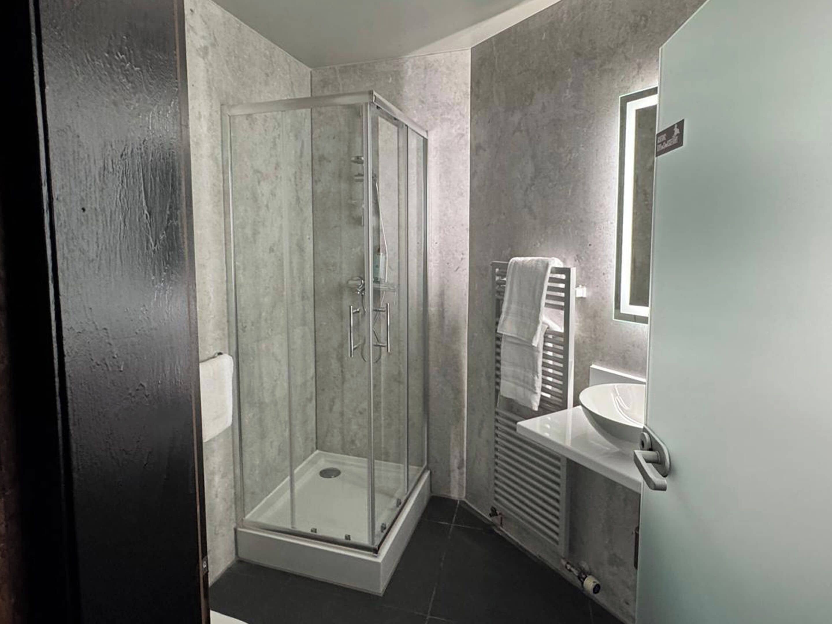 Une salle de bain moderne avec une douche à parois de verre, un lavabo blanc et un porte-serviettes.