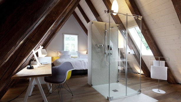 An attic bedroom with a glass shower, a desk, and a chair. - DORMERO Schwäbisch Hall (Schwäbisch Hall)
