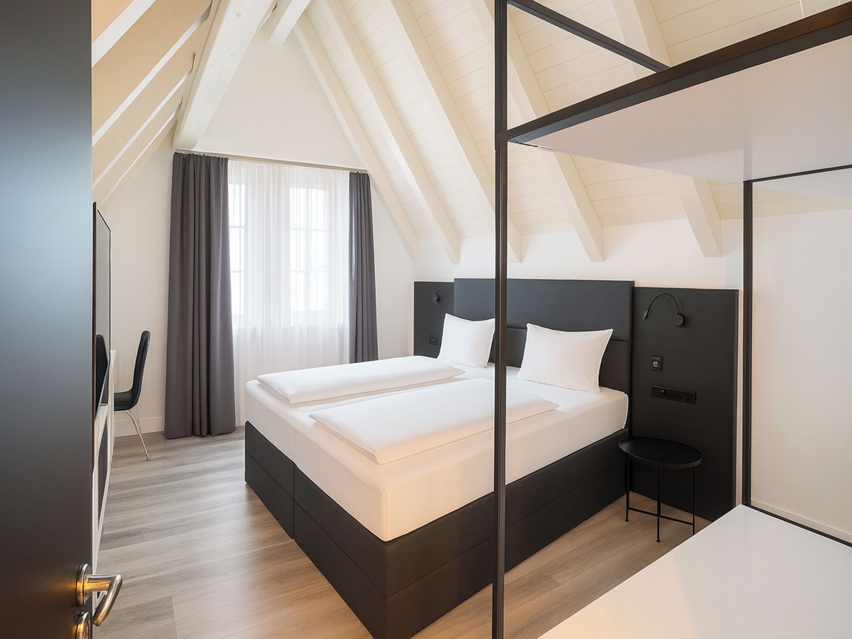 A modern hotel room with a large bed, a small table, and a mirror.