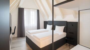 A modern hotel room with a large bed, a small table, and a mirror.
