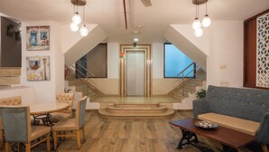 A spacious lobby with a staircase, a dining area with chairs and a table, and a sofa. - Ahuja Residency, Dlf Phase II (Gurugram)