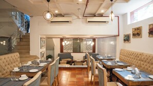 A restaurant with high tables, cushioned booths, and a staircase. - Ahuja Residency, Dlf Phase II (Gurugram)