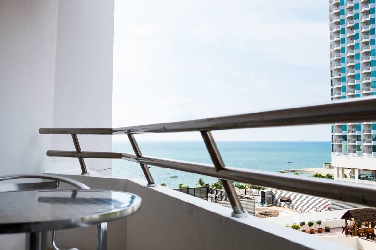 A balcony with a metal railing overlooking a beach and ocean.